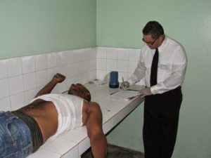 El medico legista en momento en que certificada la muerte de uno de los asesinados en la comunidad de Gen en Gaspar Hernández.