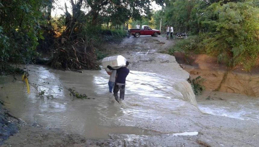 Dolientes de uno de los fallecidos se arriegan a cruzar el río con el ataúd para ser traslado al cementerio.